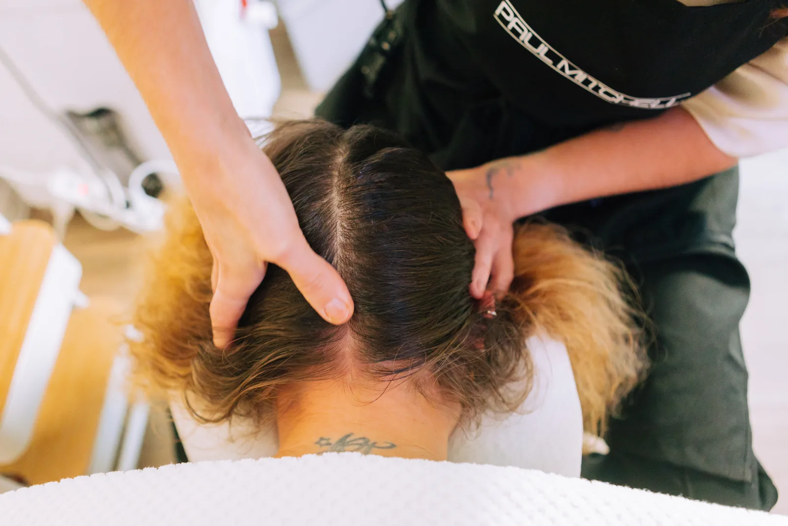 Mãos a trabalhar o couro cabeludo, a separar o cabelo na nuca
